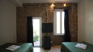 A room with two beds, a television, and a stone wall. - New Generation Hostel Belgrade Center (Belgrade)