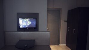 A room with a television mounted on the wall, a bench, and a wardrobe. - New Generation Hostel Belgrade Center (Belgrade)