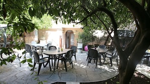 An outdoor patio with stone flooring, round tables, and chairs. - New Generation Hostel Belgrade Center (Belgrade)