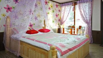 A bedroom with a wooden bed, floral wallpaper, and a view of the outdoors through a window.