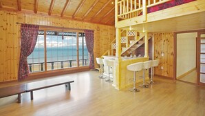 A wooden cabin with a balcony, a bar area with stools, and a bench. - Morwenna Pension (Taean)