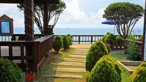 A wooden deck with a stone pathway leading to a view of the sea. - Morwenna Pension (Taean)