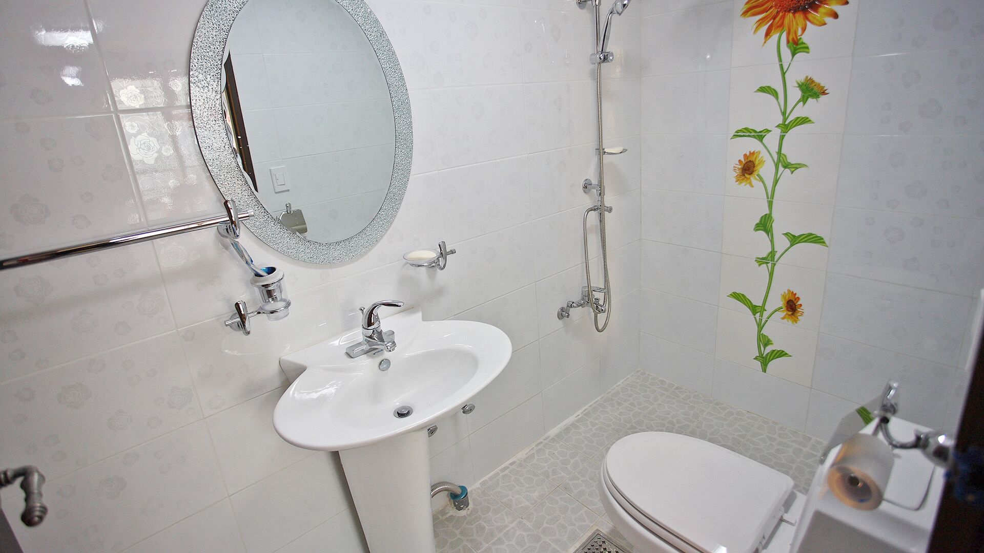 A bathroom with a white sink, mirror, shower, and toilet.