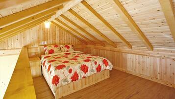 Un dormitorio con techo inclinado de madera, una cama con ropa de cama floral y paredes de madera.
