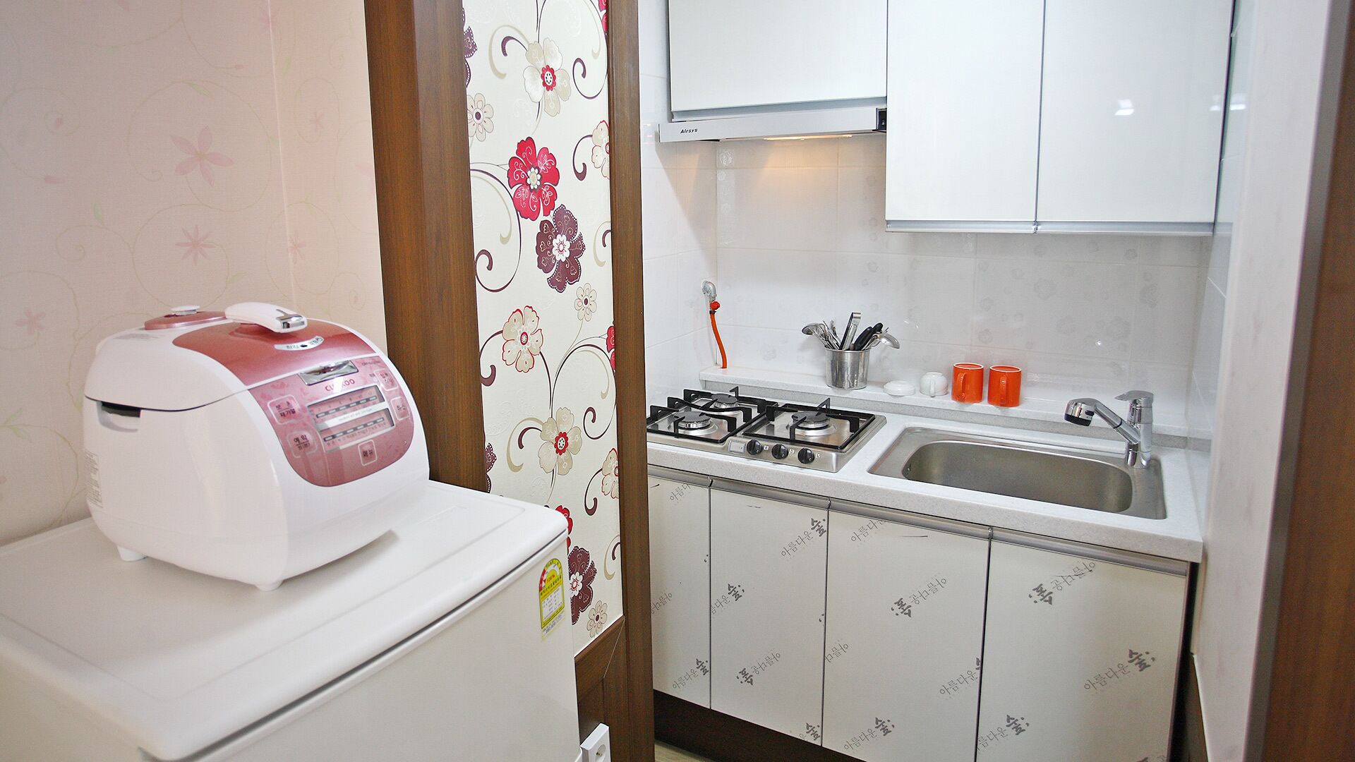 A compact kitchen with a gas stove, a sink, and a white refrigerator.