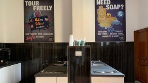 A hotel reception area with a modern design, featuring a reception desk, a coffee machine, and a large poster advertising a tour package. - New Generation Hostel Tirana Center (Tirana)