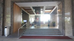 Een hotel lobby met een marmeren trap, een receptiebalie en een rode loper.