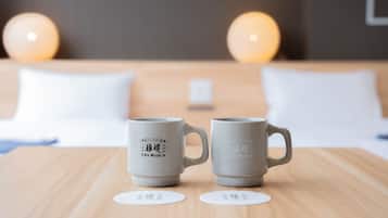 Two grey mugs with Japanese text on a wooden table in a hotel room.