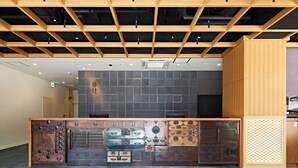 A modern kitchen with a wooden island, dark backsplash, and a ceiling with exposed beams. - HOTEL Enmichi (Kawasaki)