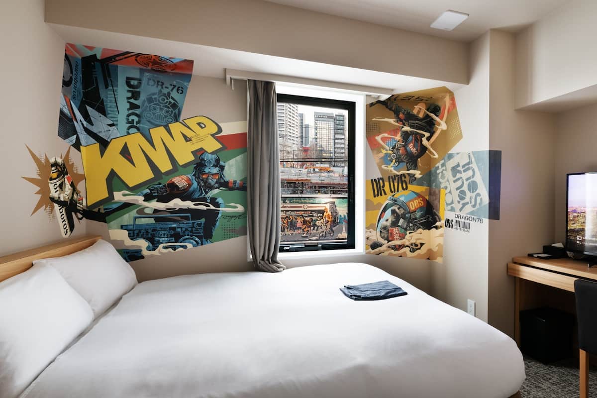 A hotel room with a large bed, a desk, and a window with curtains.