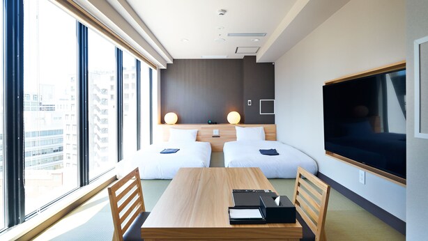A modern hotel room with a large window, two beds, a wooden table, and a flat-screen TV. - HOTEL Enmichi (Kawasaki)