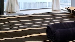 A hotel room with a large window, striped carpet, and a rolled-up blanket on the bed. - Pinnacle PJ by Flexihome (Petaling Jaya)