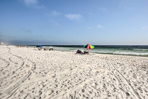 Enjoy a serene beach experience with a clear view of the ocean and plenty of space to relax under a shaded umbrella.