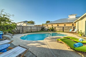 Un jardin avec une piscine, des chaises longues et une clôture en bois.