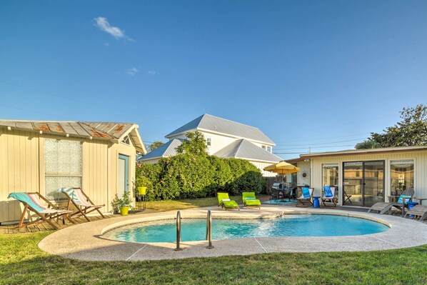 Un jardin avec une piscine, des chaises longues et un patio couvert.