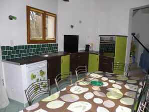 A compact kitchen with a sink, a stove, and a dining area with a table and chairs. - Villas with private pools in the Cévennes near Ardèche   (SAINT BRES)