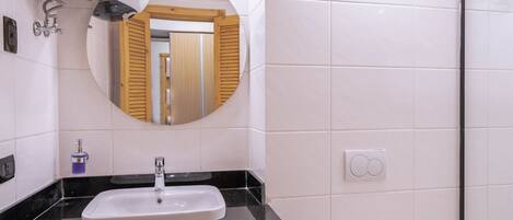 A modern bathroom with a white sink, black countertop, and a toilet.