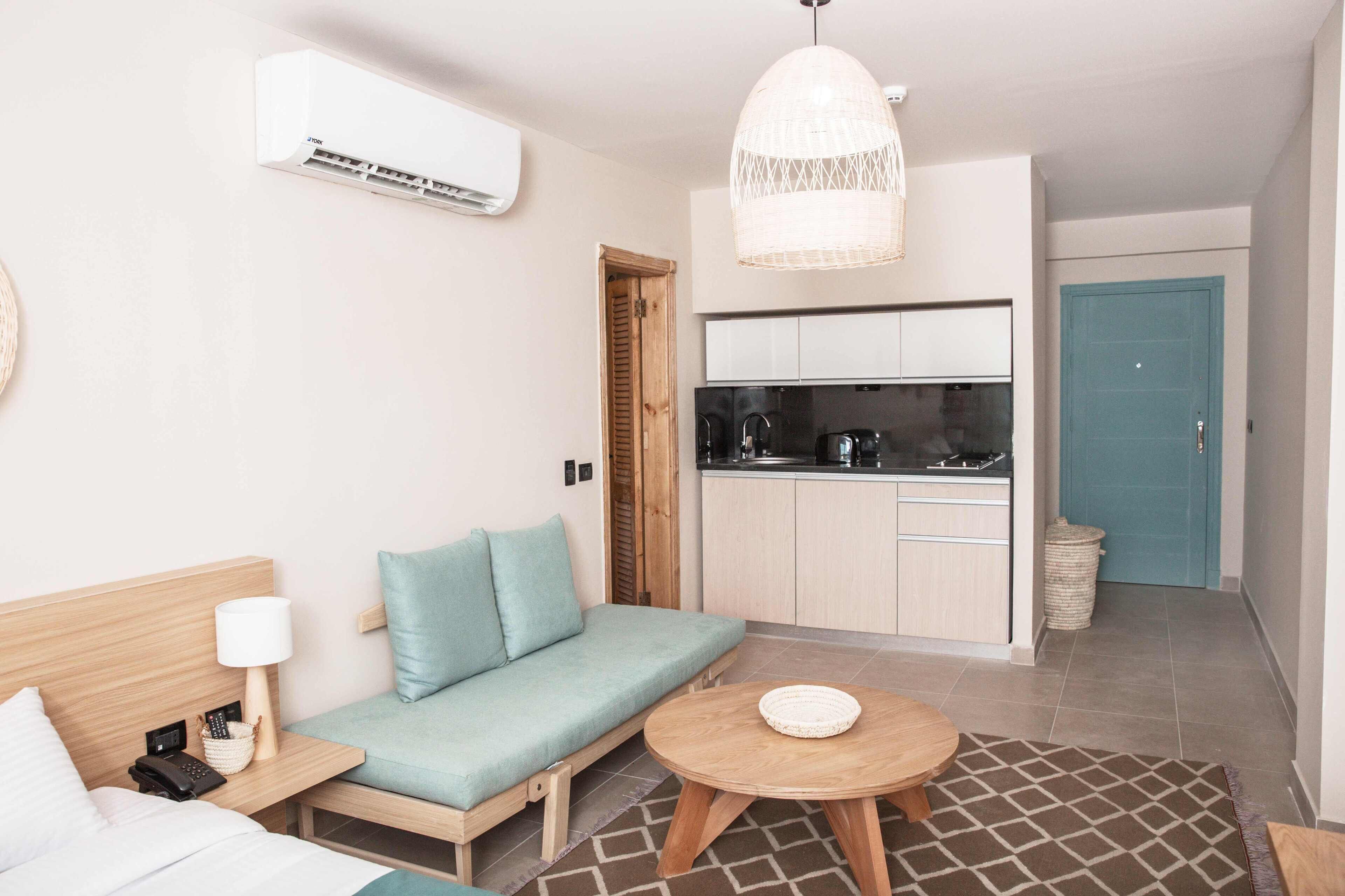 Une chambre d’hôtel compacte comprenant un lit, un canapé, un petit coin cuisine et une table à manger.