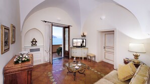 A spacious living room with a glass coffee table, a sofa, and a view of the outdoors through an open door. - Villa Alba d' Oro - Historic Luxury Villa  (Amalfi)