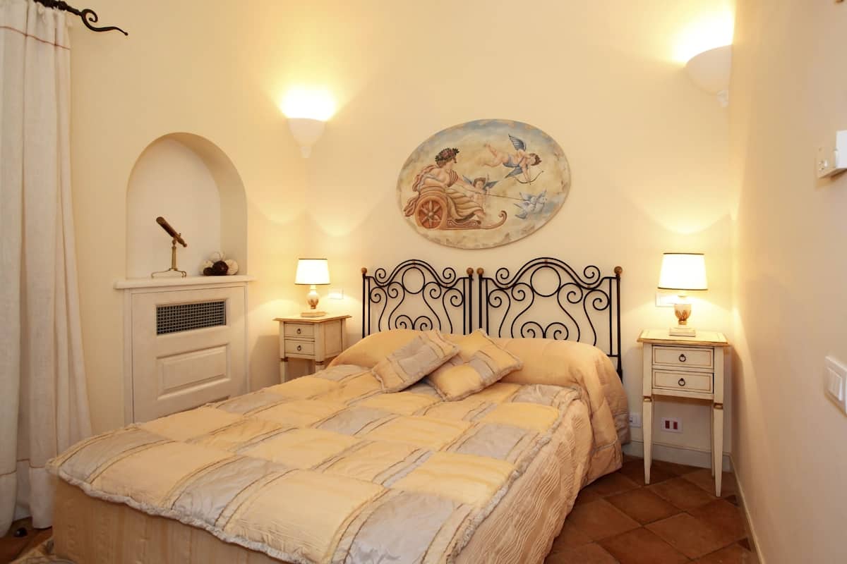 Une chambre à coucher comprenant un lit, deux tables de chevet, une lampe fixée au mur et une assiette décorative au-dessus du lit.