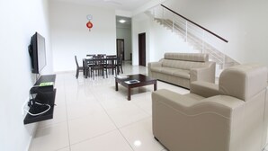 A modern living room with a sofa, coffee table, TV, and a staircase. - Kota Laksamana Comfortable Crowd by Step-In (Malacca City)