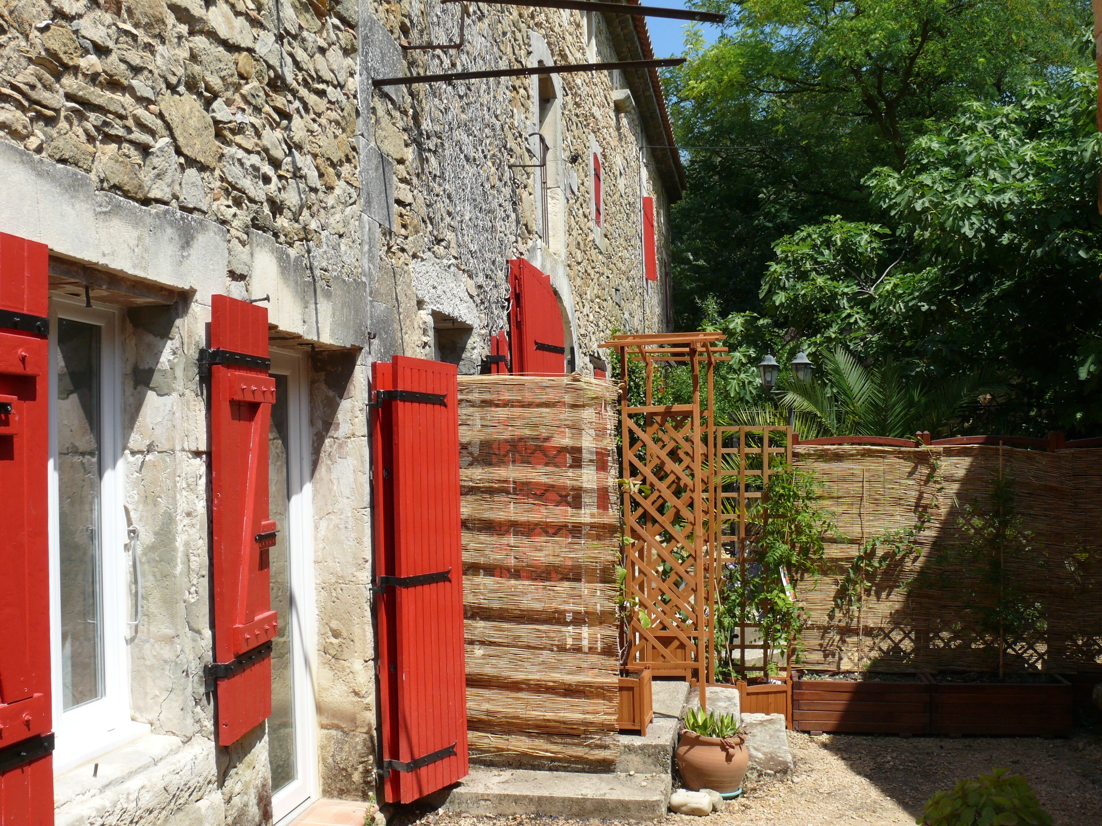 Un bâtiment en pierre avec des volets rouges et une structure en treillis de bois.