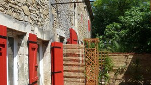 A stone building with red shutters and a wooden lattice structure. - Superb Gîte in Mas (Bollène)