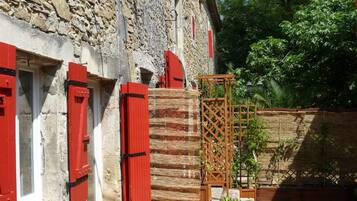 Un bâtiment en pierre avec des volets rouges et une structure en treillis de bois.