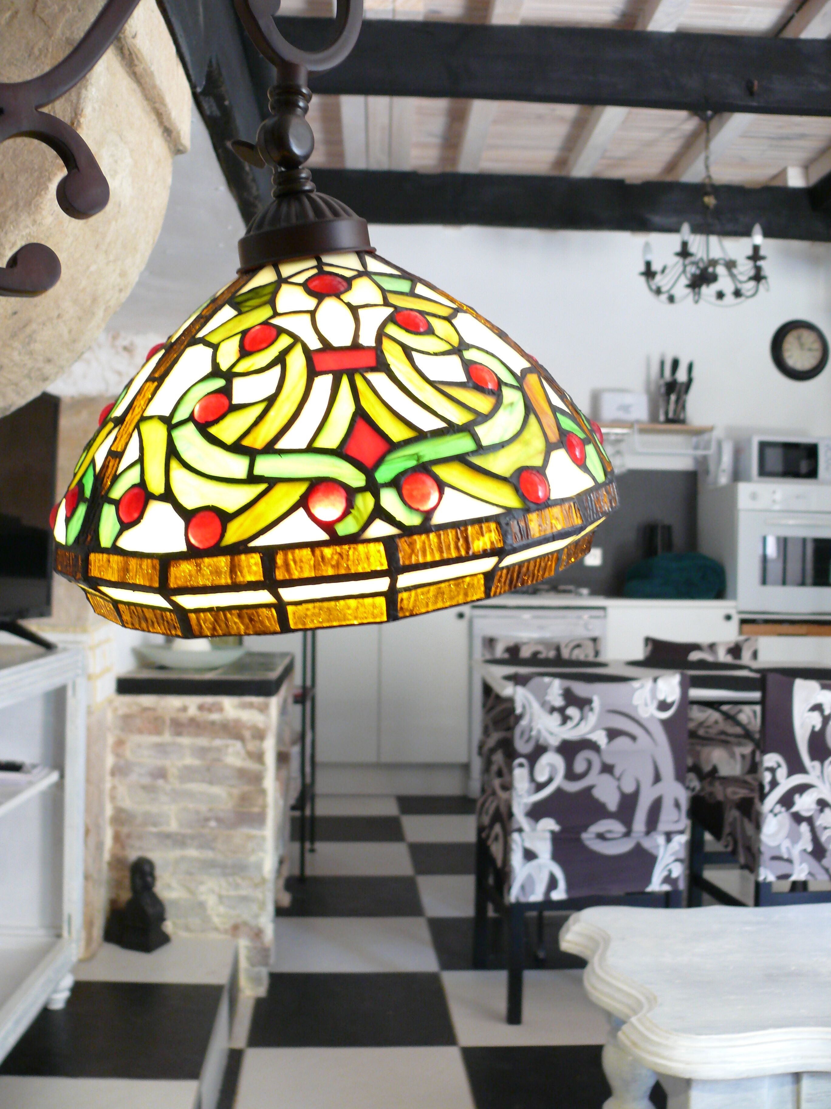 Une cuisine avec un carrelage à motifs géométriques, un luminaire décoratif suspendu et une horloge au mur.