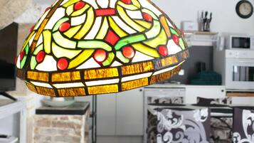 Une cuisine avec un carrelage à motifs géométriques, un luminaire décoratif suspendu et une horloge au mur.