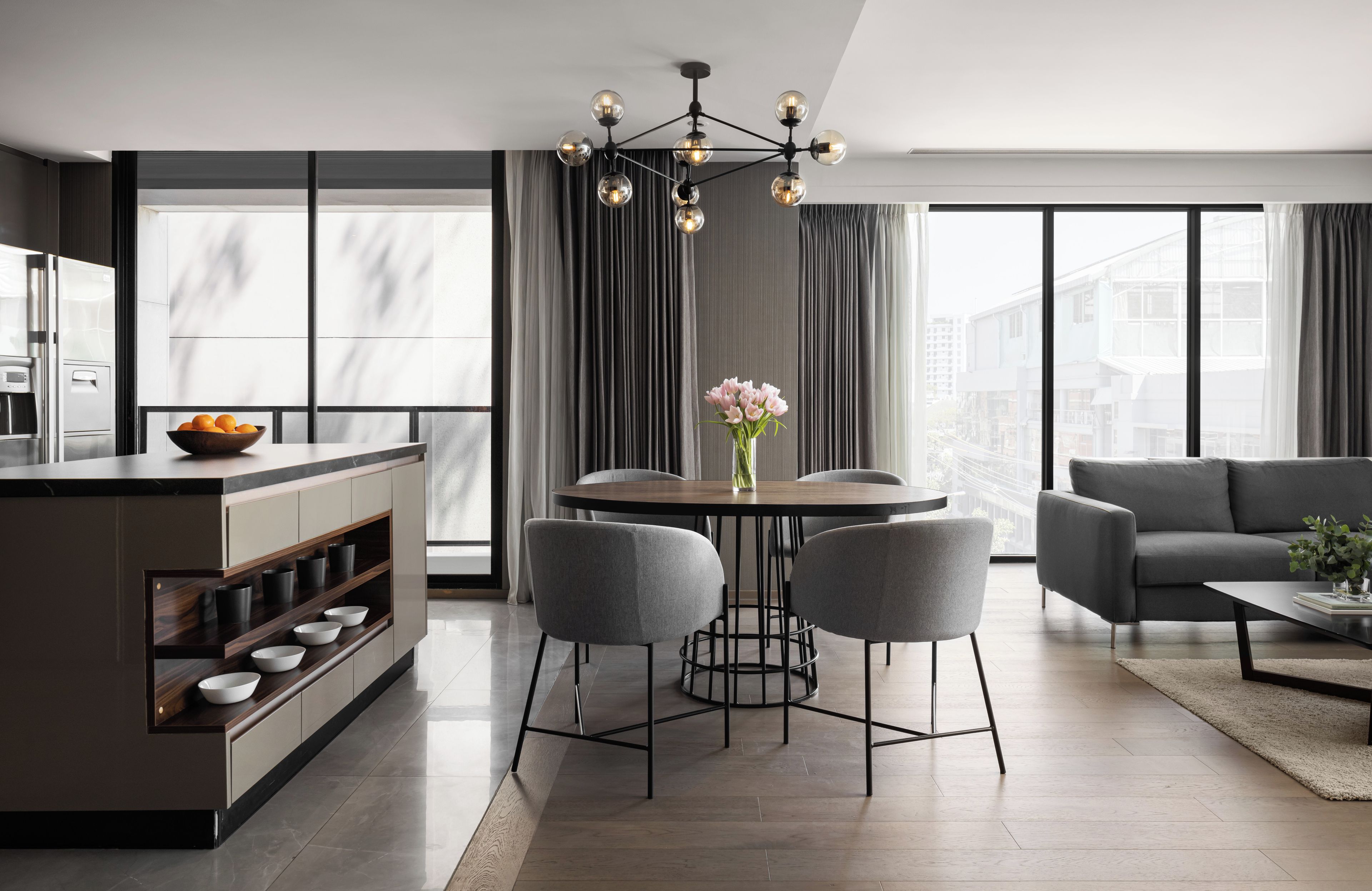 Een moderne keuken met een centraal eiland, een eethoek met een ronde tafel en vier stoelen, en een zithoek met een bank en salontafel.