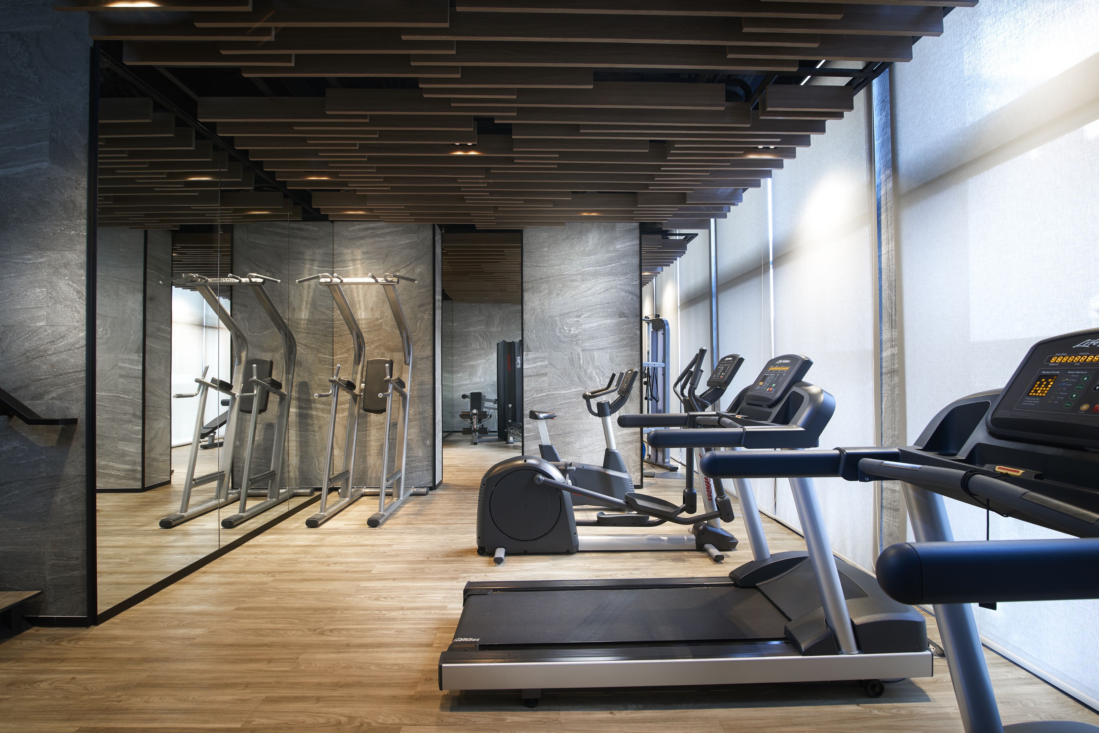 Une salle de sport moderne équipée de tapis de course, de vélos elliptiques et de poids libres.