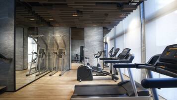 Un gimnasio moderno con cintas de correr, elípticas y pesas libres.