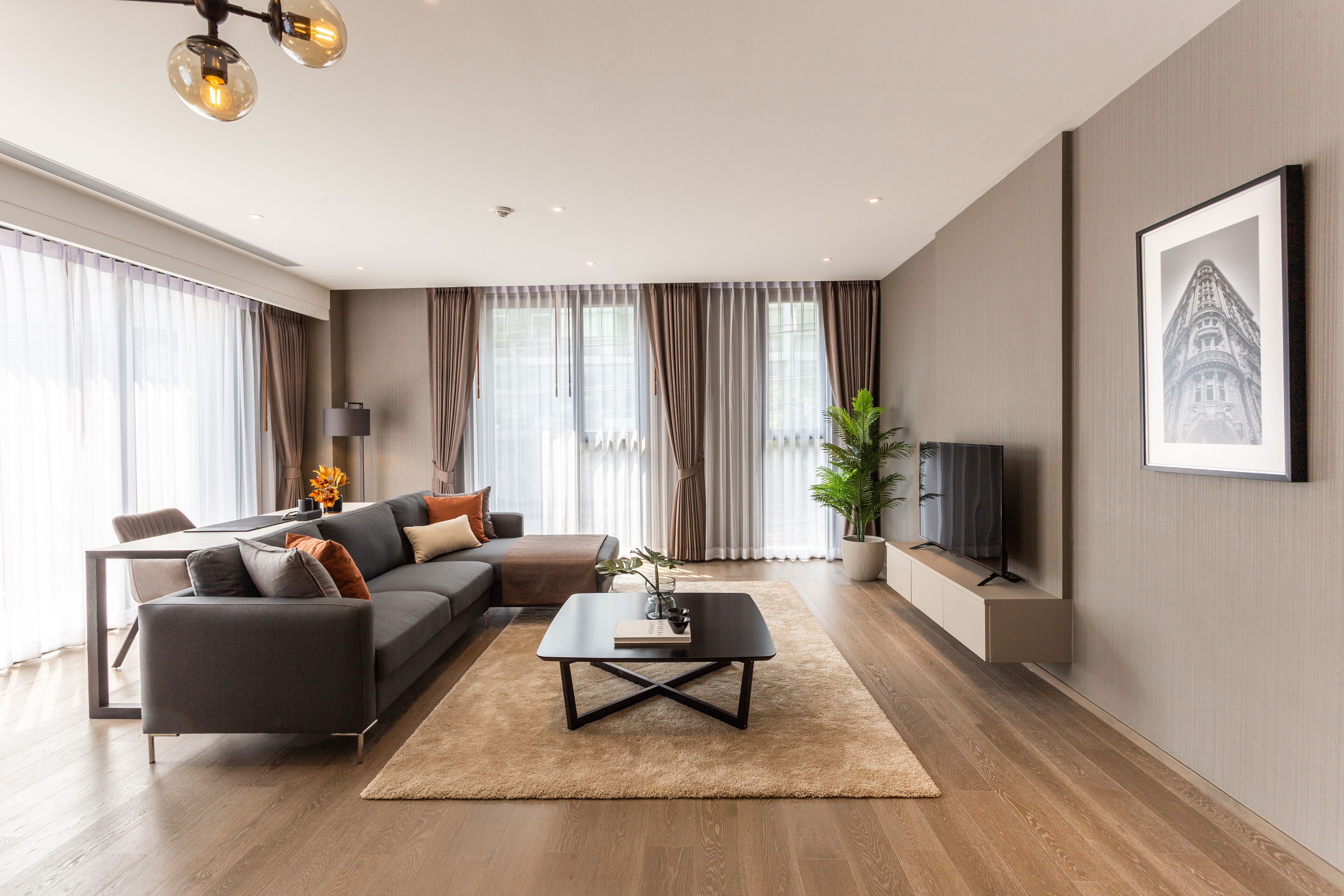 A modern living room with a sectional sofa, a coffee table, and a flat-screen TV.