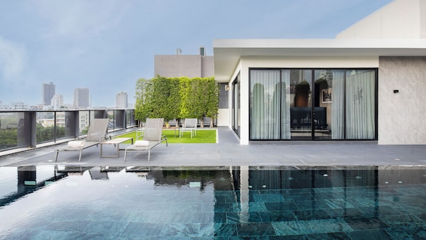 Et tag med evigheds-pool og udsigt over byen, moderne arkitektur og udendørs møbler.