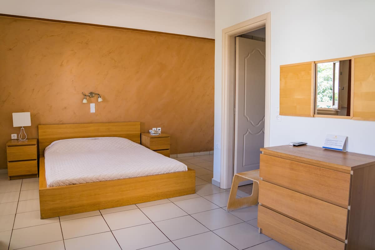 Un dormitorio con cama de madera, mesitas de noche, cómoda y espejo.