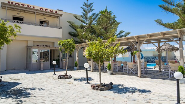 A hotel courtyard with a reception area, outdoor seating, and a pool area. - Rena Hotel (Santorini)