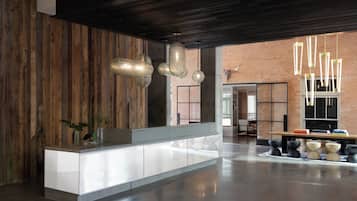 A modern interior with a wooden accent wall, a white reception desk, and a brick wall in the background.