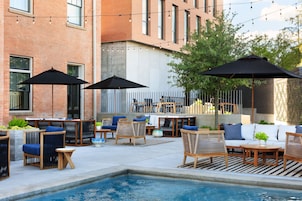 An outdoor patio area with seating, a pool, and string lights.