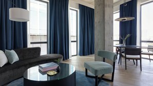 A modern living room with a sofa, a glass coffee table, and a dining area with chairs and a table. - Kimpton Pittman Hotel – Downtown Dallas by IHG (Dallas)