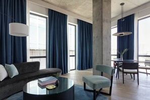 A modern living room with a sofa, a glass coffee table, and a dining area with chairs and a table. - Kimpton Pittman Hotel – Downtown Dallas by IHG (Dallas)