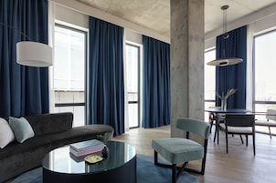 A modern living room with a sofa, a glass coffee table, and a dining area with chairs and a table.