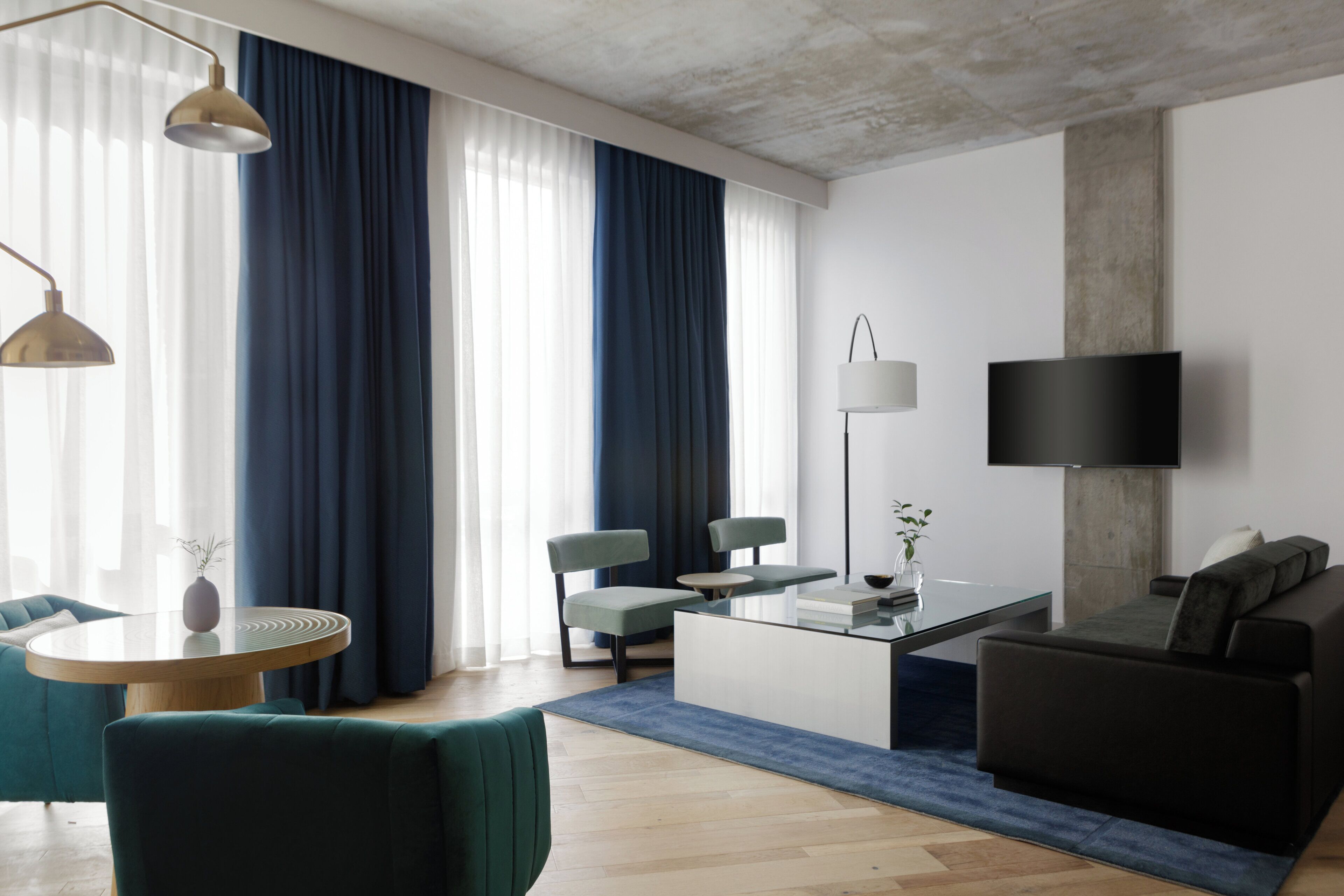 A modern living room with a sofa, chairs, a coffee table, and a TV mounted on the wall.