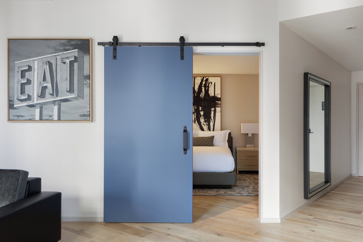 A room with a sliding door, a bed, a bedside table, a lamp, and a framed picture on the wall.