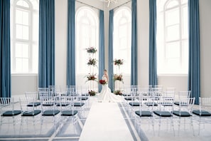 A wedding ceremony setup with a bride in a white dress, clear chairs, and blue curtains. - Kimpton Pittman Hotel – Downtown Dallas by IHG (Dallas)