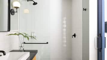A modern bathroom with a white tiled shower, a black bathtub, and a mirror with a black frame.