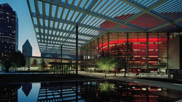A modern building with a glass facade and a reflective pool in front.