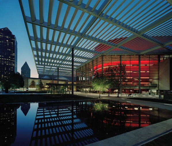 A modern building with a glass facade and a reflective pool in front.
