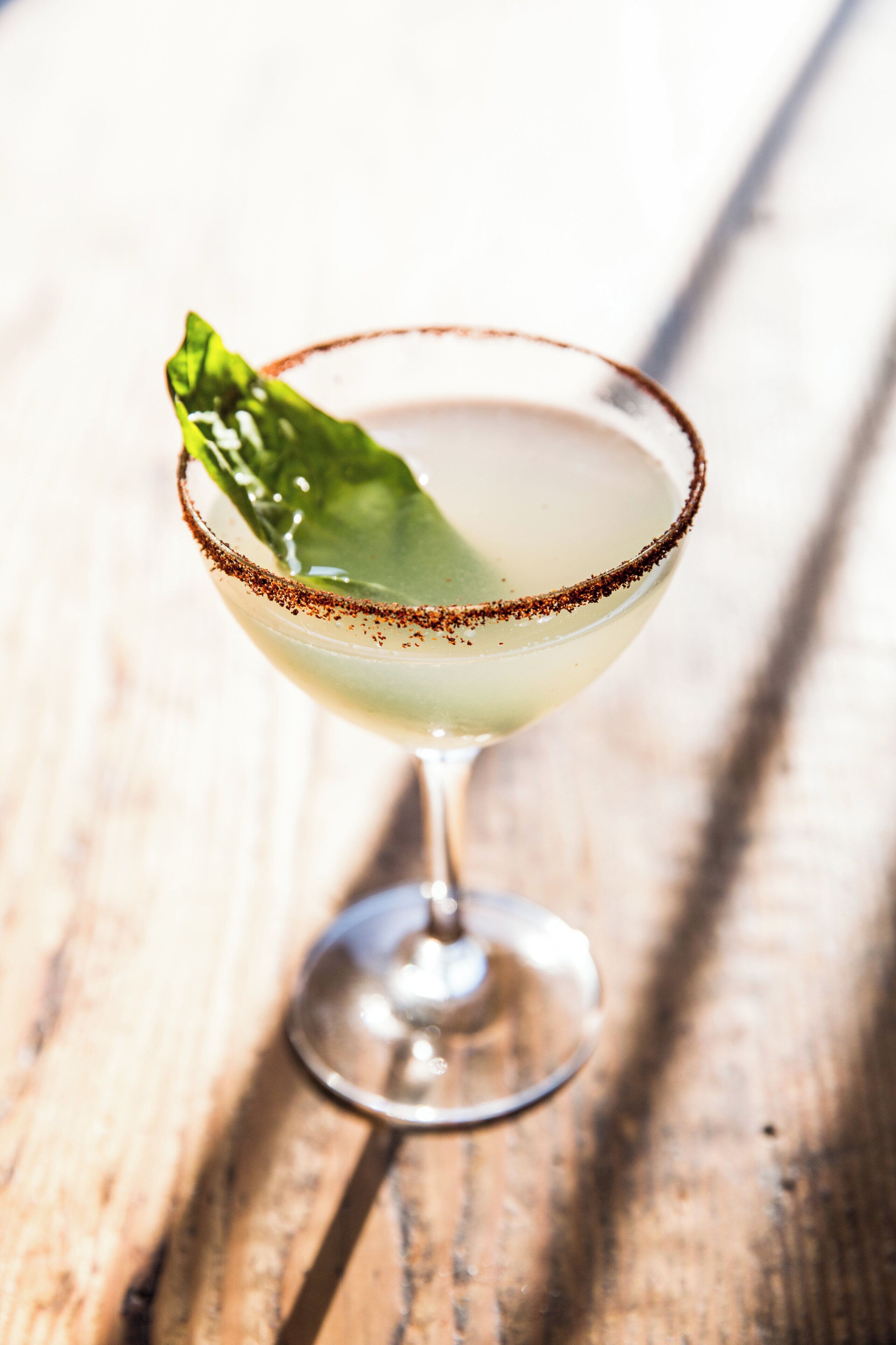 A cocktail glass with a salted rim on a wooden surface.
