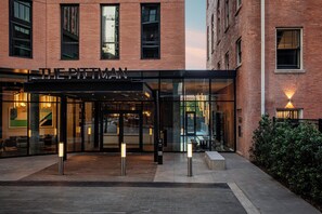 A hotel entrance with a glass facade, a black awning, and a brick building facade. - Kimpton Pittman Hotel – Downtown Dallas by IHG (Dallas)